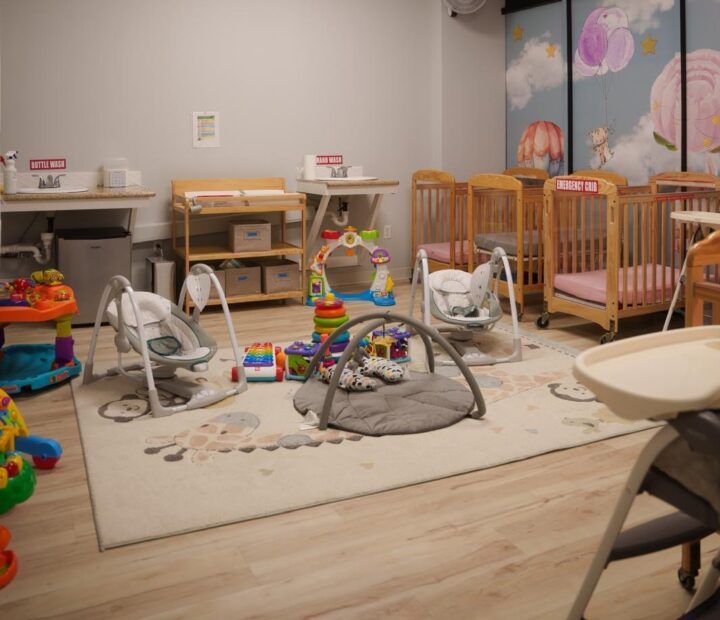 Clean infant room with cribs, activity equipment and care stations