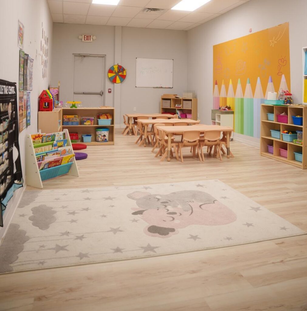 Bright preschool classroom with learning tables, books and activity areas at Starz R Us